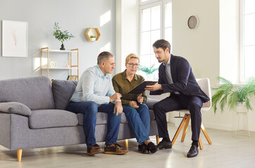Elderly couple consulting with financial advisor about investments or real estate. Young male...