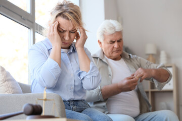 Obraz premium Stressed mature woman and her husband taking wedding ring off finger at divorce lawyer's office