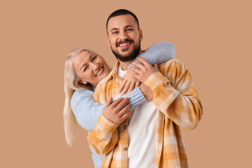 Fototapeta premium Mature woman hugging her son on beige background