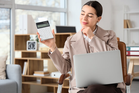 Thoughtful businesswoman with calculator and laptop sitting in office