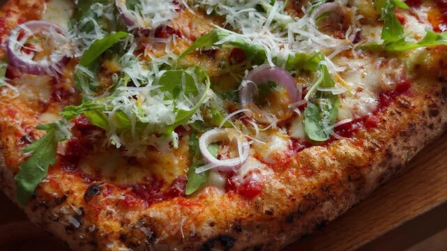 An overhead, mouth-watering shot of a hot, freshly baked gourmet pizza. The toppings include vibrant rocket salad, savory meat, and perfectly melted mozzarella cheese bubbling across the crust. 