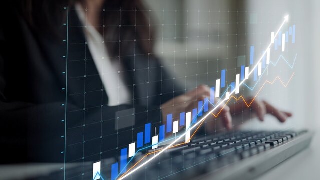 A businesswoman focuses on data trends with a graphical overlay, symbolizing financial growth in a modern office environment while using a computer keyboard. Copula