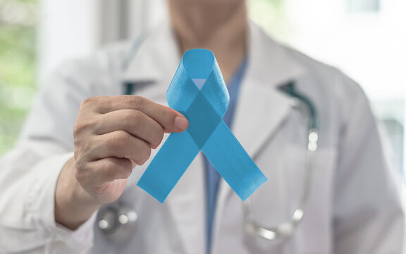 Prostate cancer blue awareness ribbon for men health and male mental health care concept with pale light blue bow color on medical doctor's hand in hospital background