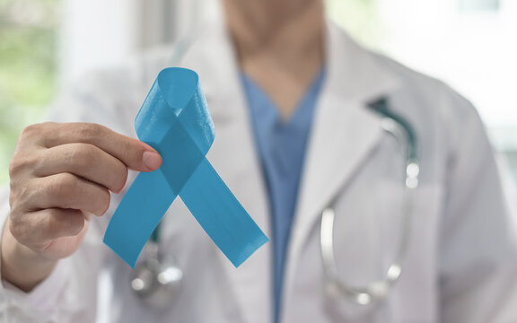 Prostate cancer blue awareness ribbon for men health and male mental health care concept with pale light blue bow color on medical doctor's hand in hospital background