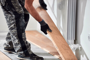Professional handyman installing laminate flooring in a new apartment.
