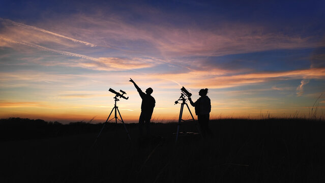 Amateur astronomer using telescope for watching stars, Moon, planets and other celestial objects from a field in nature.
