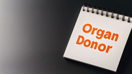 A notepad with the phrase "Organ Donor" prominently displayed in orange text against a dark background.