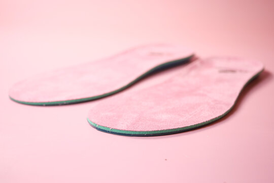 Pink shoe insoles displayed on a smooth surface