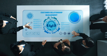 A diverse business team collaborates around a modern table with a digital interface, focusing on customer relationship management strategies and insights. Trope