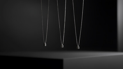 Silver pendant necklaces hang against a dark backdrop. Each features a minimalist rectangular pendant on delicate chains, showcased in a sleek and modern setting.