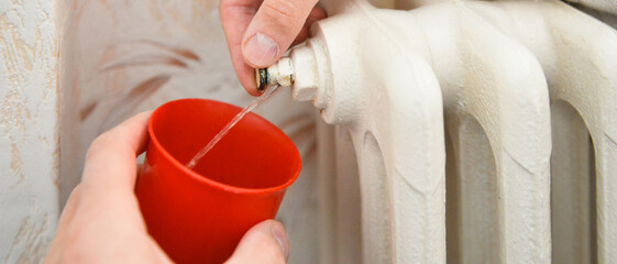Évacuation de l'air d'un radiateur en fonte jusqu'à ce que l'eau coule en continu, format...