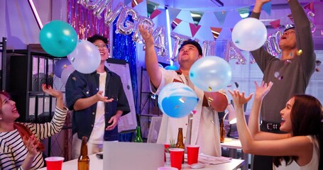 Joyful young Asian coworkers toss balloons in the air during a fun celebration at work. A colorful office party scene full of laughter, energy, and happy team spirit for any festive occasion. - Powered by Adobe