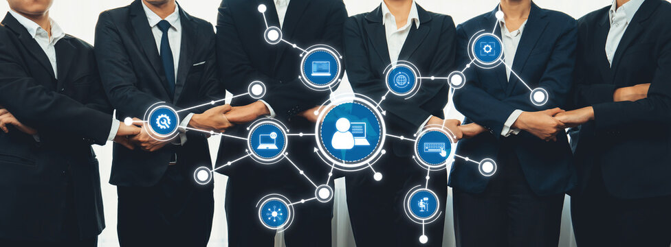 A group of business professionals standing united, symbolizing collaboration and digital connectivity with technology icons in a modern corporate setting. Amity - Powered by Adobe