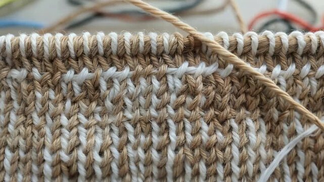 Close-up view of a knitted fabric with a two-tone pattern, showing texture and detail.
