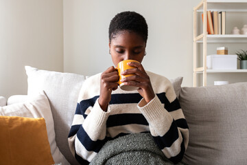 Woman relaxing on sofa drinking hot beverage at home