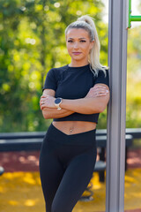 Confident woman standing outdoors at a fitness park with a smartwatch