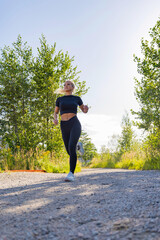 Young woman running outdoors on a scenic trail in activewear gear