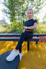 Young woman using smartwatch during outdoor workout on sunny park trail