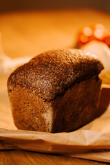 Fresh artisan bread loaf on brown paper with colorful ingredients in the background
