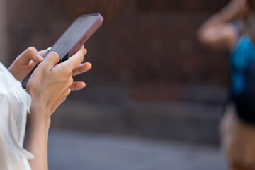 Person's hands using smartphone outdoors in the city. Communication and technology while traveling