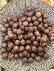 Whole macadamia nuts in a woven basket on wooden table background