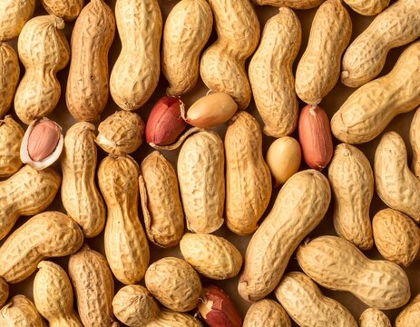 Close-up of a heap of peanuts in their shells and shelled kernels on a beige surface