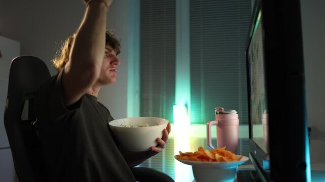 Young man reacts with shock and anger after losing an online bet hitting the monitor with frustration neon light fills the room creating a tense emotional moment of disappointment and impulsive reacti