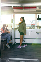 Young woman with prosthetic leg standing on an urban bus, commuting on public transport during daytime