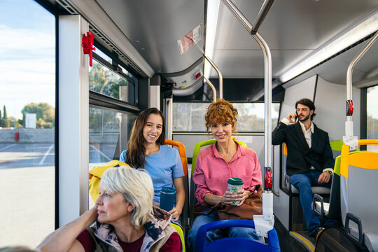 People of various ages traveling seated inside a modern city bus enjoying their journey, representing urban public transport - Powered by Adobe
