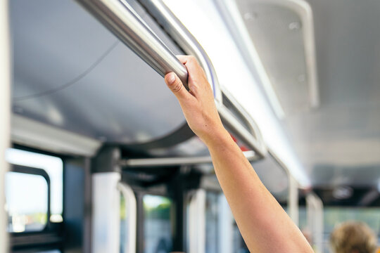 Commuter hand gripping a support handle inside a public city bus, representing urban transportation, safety, and daily travel