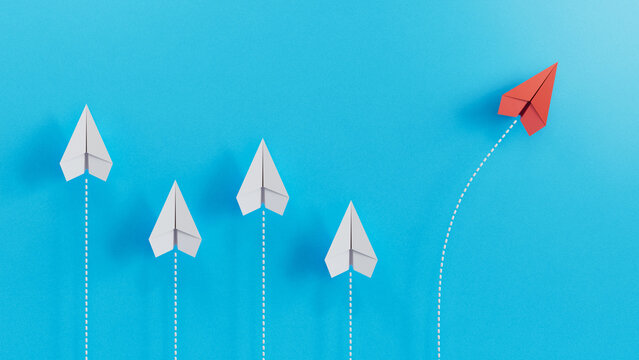 Red Paper Airplane Taking a Distinct Path Away from White Counterparts on Blue Background