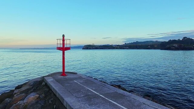 Scenic, real-time shot of colorful traditional fishing boats moored in the small, quaint port of Cand&aacute;s, Asturias, Spain. Historic coastal town architecture surrounds the harbor on a cloudy day