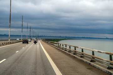 Oresund Bridge carrying road traffic across the strait between Denmark and Sweden under a cloudy sky, connecting Copenhagen and Malmo.