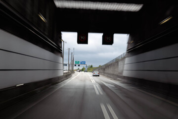 Driving toward Oresund Bridge tunnel entrance on cloudy day, highway lanes leading into modern concrete transport connection. 