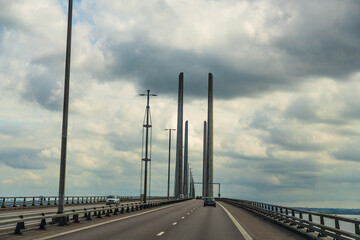 Cars travelling along a highway on the Oresund Bridge connecting Malmo, Sweden, and Copenhagen, Denmark, under a cloudy sky. 
