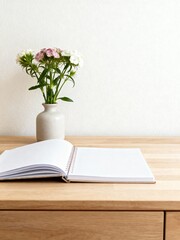 A blank spiral notebook and a vase of fresh flowers on a light wood desk. Vertical minimalist home office scene with copy space for text