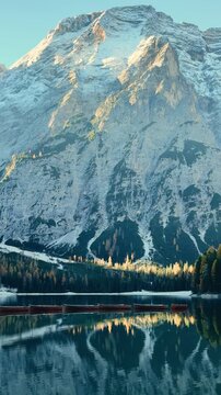 Beautiful Lago di Bries in Italy reflecting snow-capped mountains and lush forests at dawn