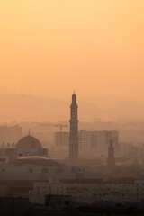 Muscat city skyline with mosque and minaret at sunset