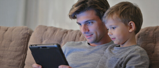 Together in Learning: A tender moment unfolds as father and son bond while exploring the world through the screen of a tablet. It's a scene of shared discovery and modern family life.