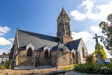Fototapeta premium Historic church building featuring a bell tower and stone calvary under a blue sky