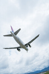 Obraz premium Commercial airliner flying with landing gear down against a cloudy sky