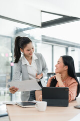 Happy asian businesswoman in teamwork and collaboration during meeting. Two professional colleagues discuss document with smile in modern office
