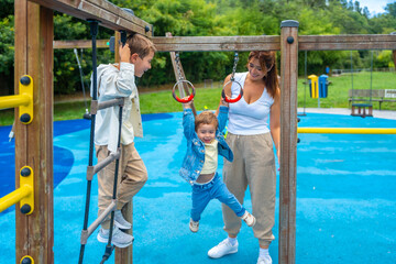 Happy children playing with mother on playground jungle gym
