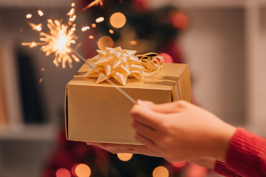child's hand holding a Christmas gift and a sparkler