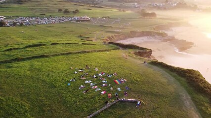 A diverse group of adults practicing yoga together on a sandy beach during sunset. This clip highlights community, healthy living, inclusion, fitness, and collective wellness outdoors