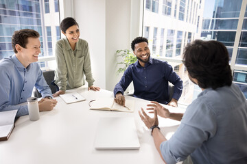 Laughing businesspeople having fun at table enjoy guidance of leader