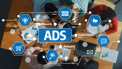 A top-down view of a creative team collaborating on advertising strategies using technology and data visuals, focusing on social media and ad campaigns in an office setting. Amity