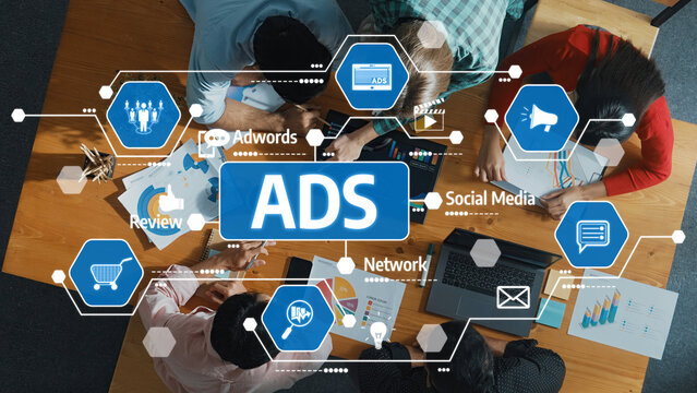 A top-down view of a creative team collaborating on advertising strategies using technology and data visuals, focusing on social media and ad campaigns in an office setting. Amity