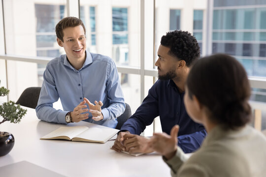 Smiling gen z male office worker speak to diverse colleagues - Powered by Adobe