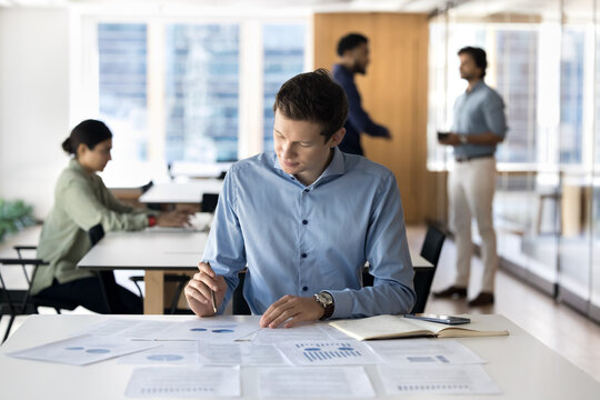 Pensive young businessman review statistic data in charts graphs